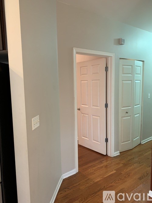 A white door is open to a room with wooden floors.