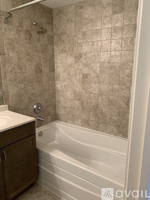 A bathroom with a tiled shower and a white bathtub.
