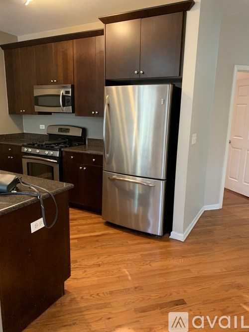 A kitchen with a stainless steel refrigerator and wooden cabinets.