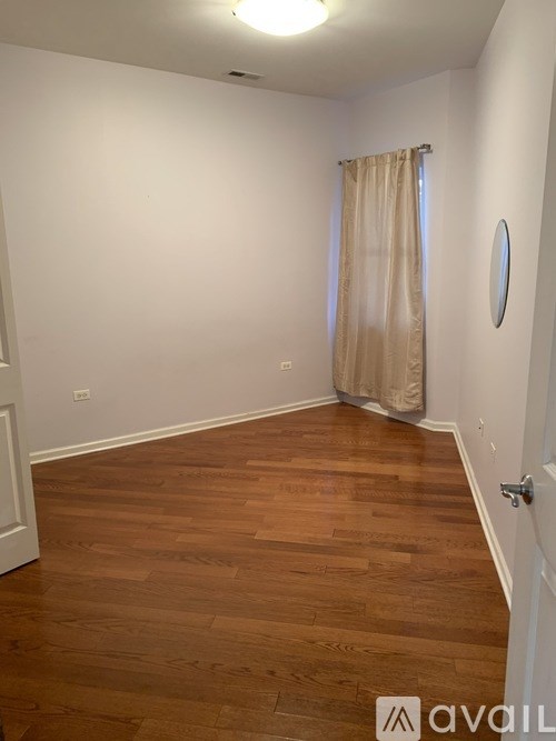 A room with wooden flooring and a beige curtain.