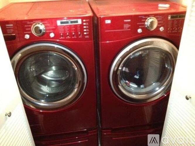 Two red washing machines in a laundry room.