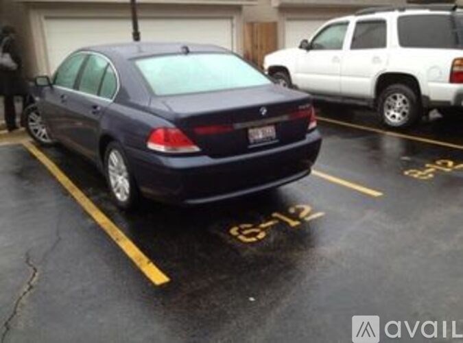A dark blue car is parked in a parking space with yellow lines.