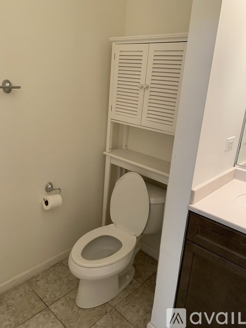 A white toilet in a bathroom with a cabinet above it.