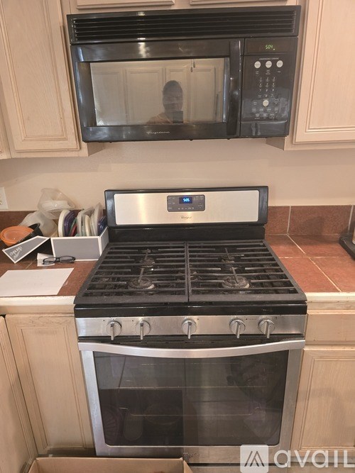 A black stove top oven with a silver handle and a silver microwave above it.