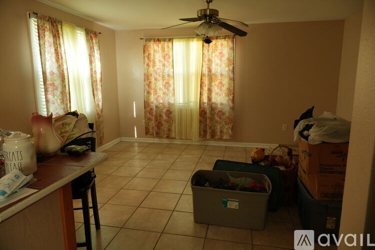 A room with a fan, a table with a vase and a chair.