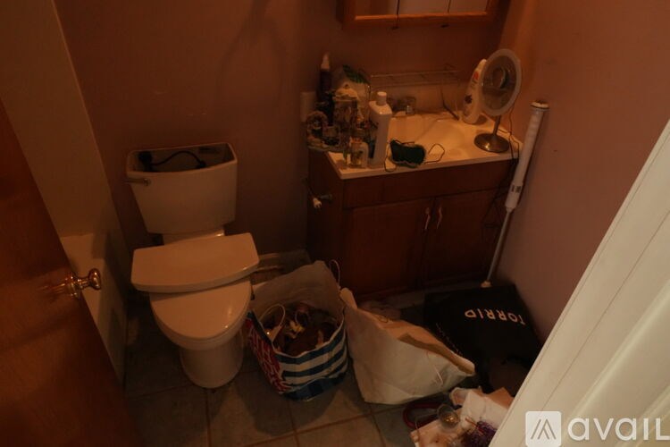 A bathroom with a toilet, sink, and a basket of items on the floor.