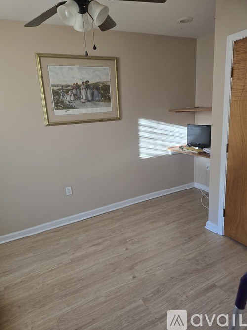A room with a ceiling fan and a painting on the wall.