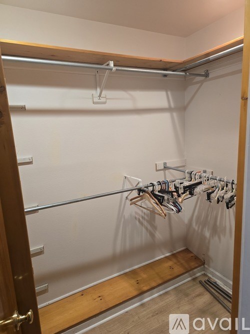 A wooden closet with clothes hanging on a rail.