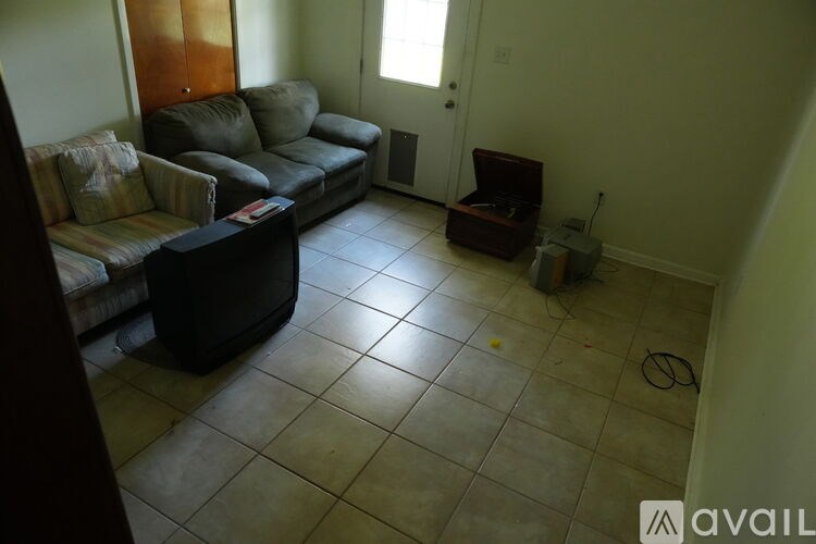 A living room with a couch, a coffee table, and a vacuum cleaner.