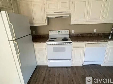 A white stove and oven in a kitchen with wooden floors and white cabinets.
