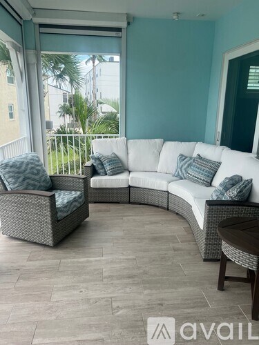 A patio with a white couch and a grey chair.