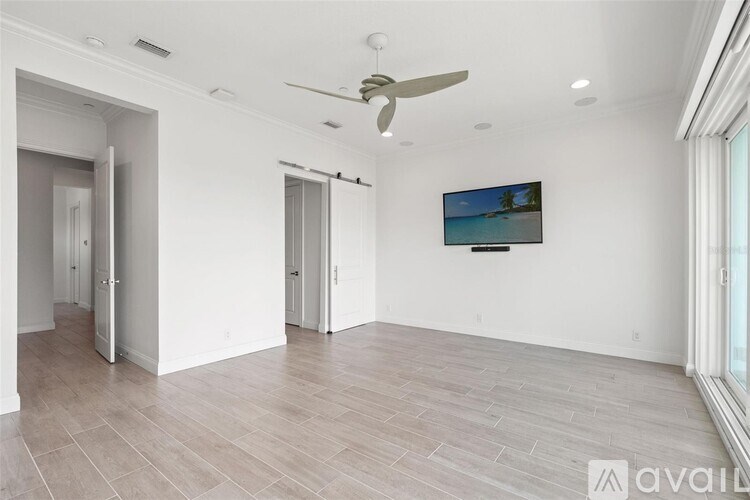 A spacious room with a ceiling fan and a television mounted on the wall.