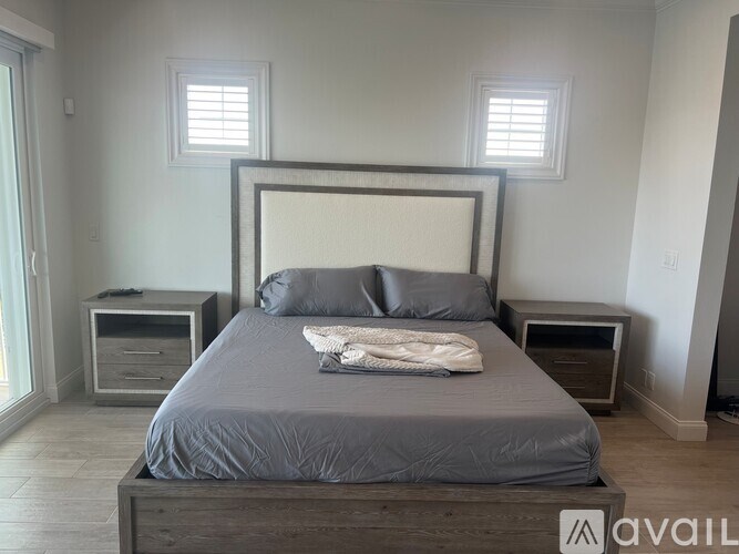 A bedroom with a bed, nightstands, and a window.