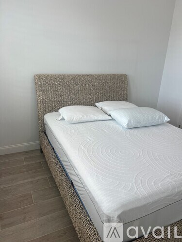 A bed with a white mattress and two white pillows sits against a wall.