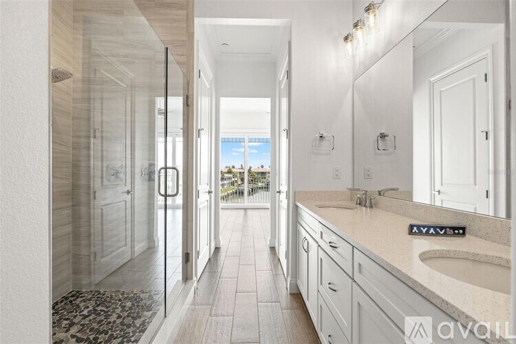 A bathroom with a glass shower door and a sink with a granite countertop.