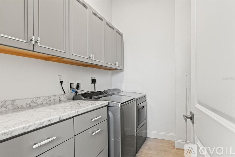 A kitchen with grey cabinets and a marble countertop.