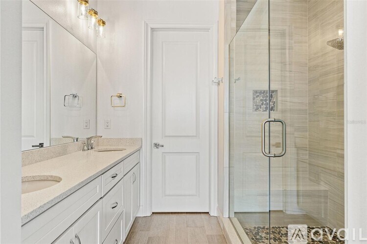 A white bathroom with a glass shower door and a white sink.