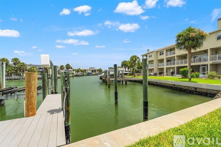 A wooden dock extends into a green waterway with buildings in the background.