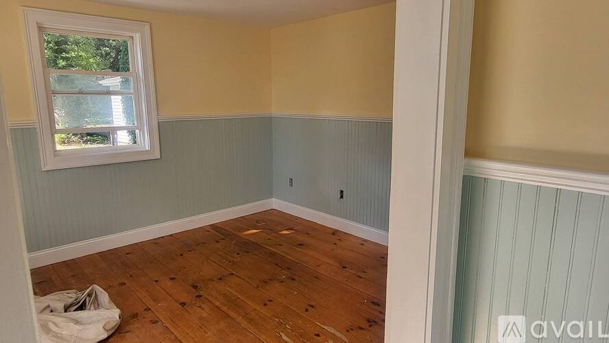 A room with wooden flooring and a window.