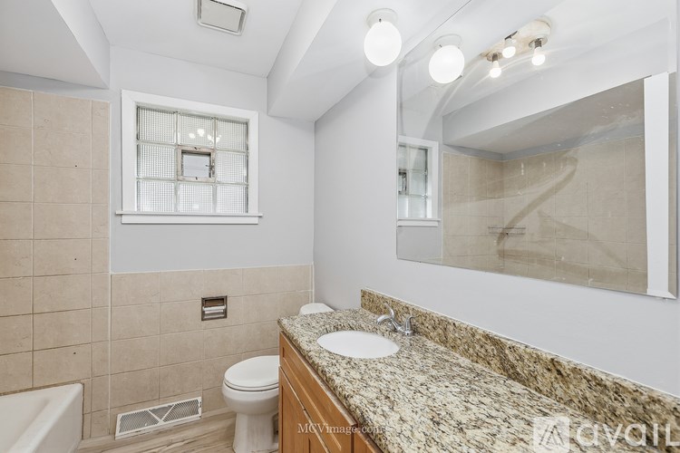 A bathroom with a marble countertop and a large mirror.