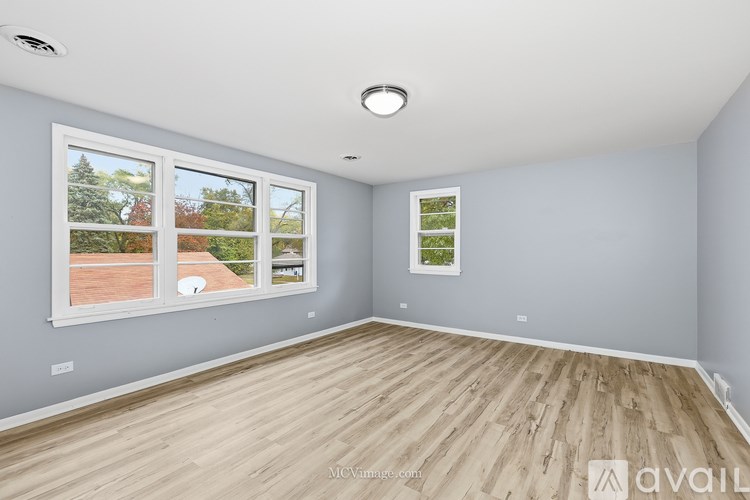 A room with wooden flooring and a large window showing an outdoor view.