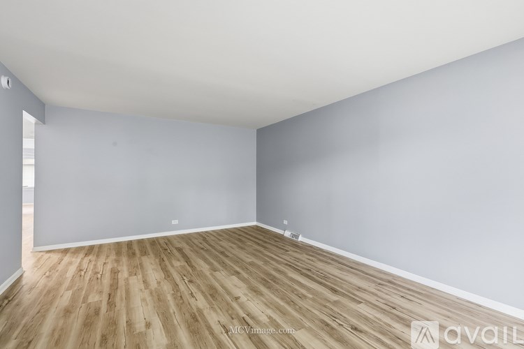 A room with wooden flooring and white walls.