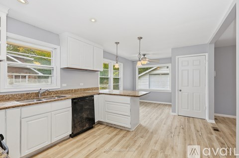 A kitchen with white cabinets and a wooden floor.