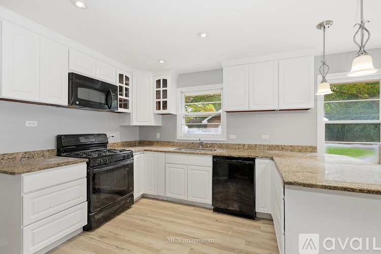 A kitchen with white cabinets and a granite countertop.