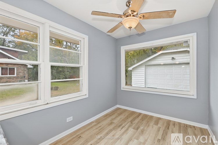 A room with a ceiling fan and two windows.