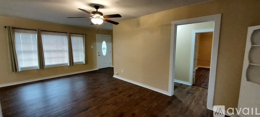 A spacious room with a ceiling fan and a door leading to another room.