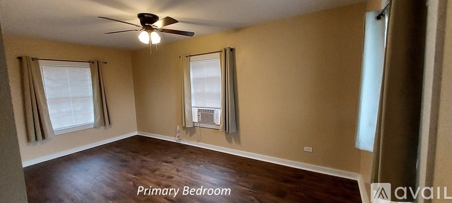A bedroom with a ceiling fan and two windows.