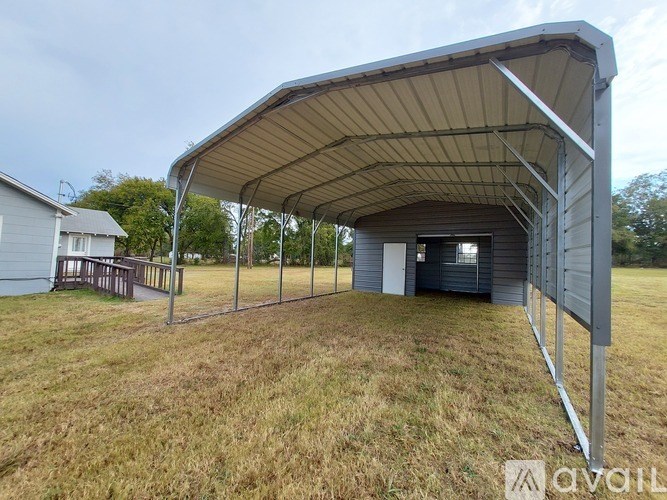 A covered outdoor area with a white building in the background.