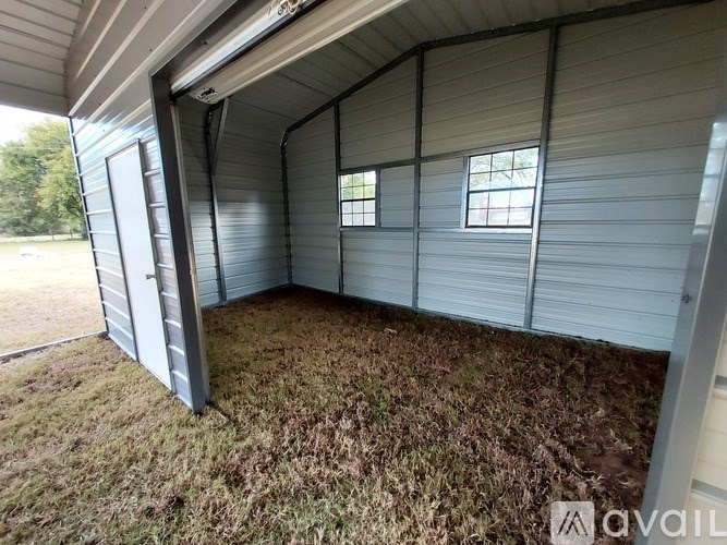 A storage shed with a grey roof and walls, and a brown carpeted floor.