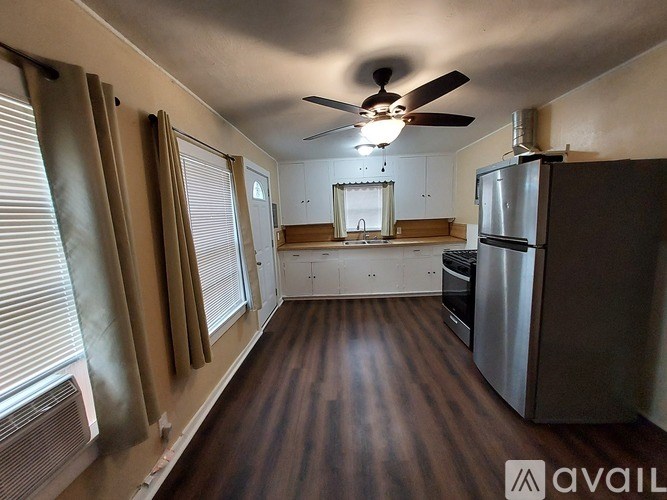 A kitchen with a refrigerator, oven, and a fan on the ceiling.