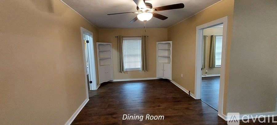 A dining room with wood floors and a ceiling fan.
