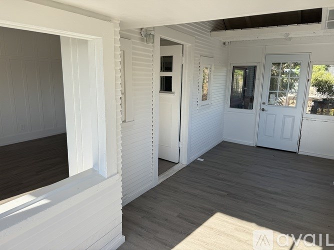 A white room with wooden floors and a white door.