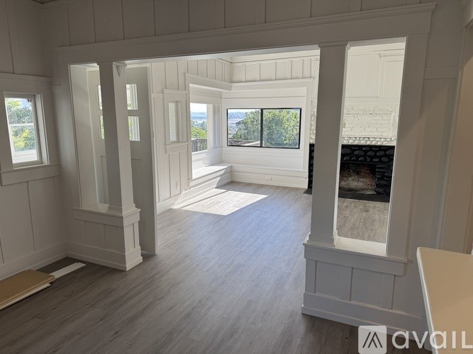 A spacious room with white walls and a large window overlooking a balcony.