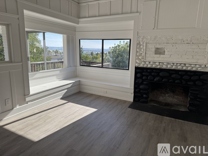 A large, empty room with a fireplace and a view of the outdoors through the windows.