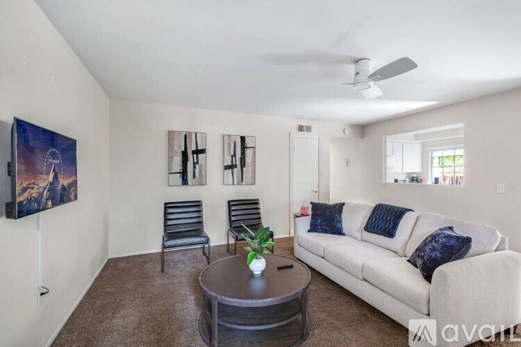 A living room with a couch, chairs, and a painting on the wall.