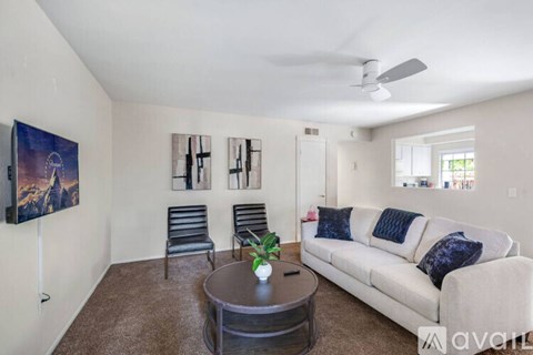 A living room with a couch, chairs, and a painting on the wall.