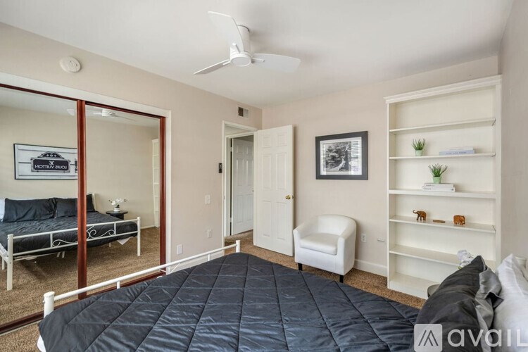 A bedroom with a bed, chair, and shelves.