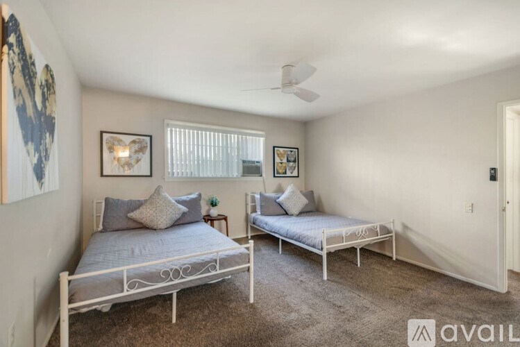 A bedroom with two beds and a ceiling fan.