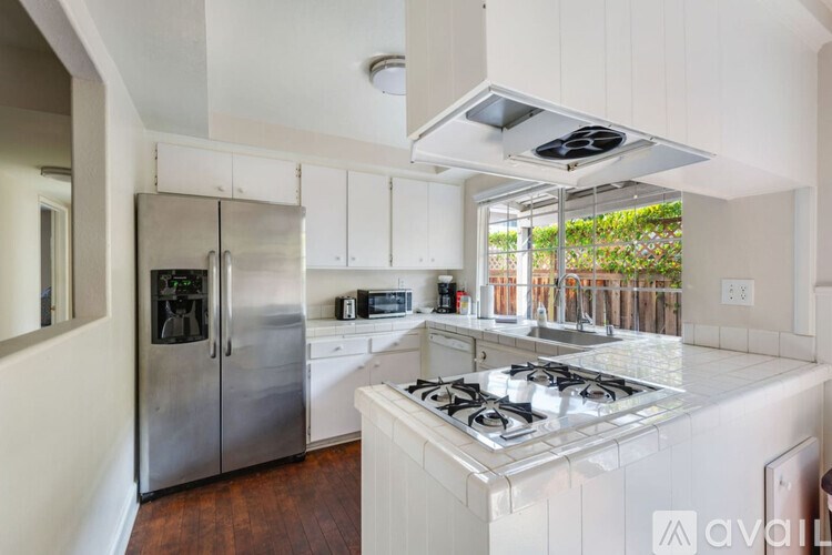 A modern kitchen with a stainless steel refrigerator and a white stove top.