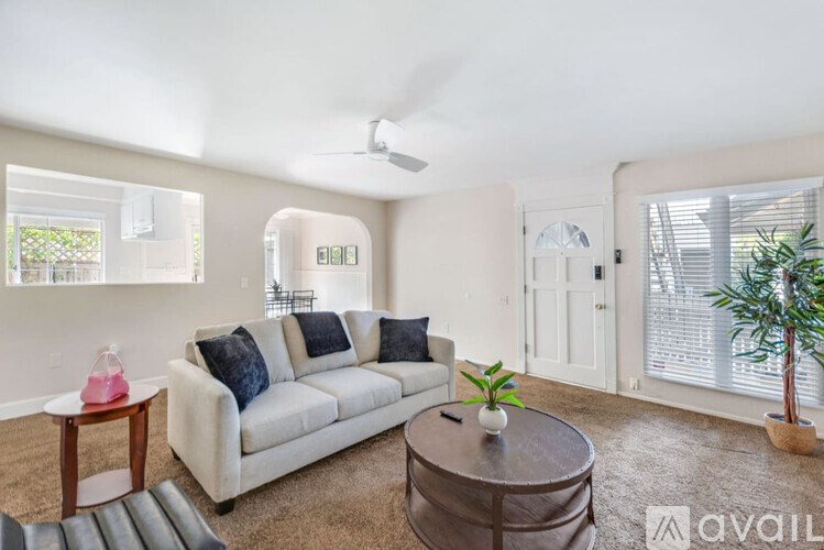 A living room with a white couch and a ceiling fan.