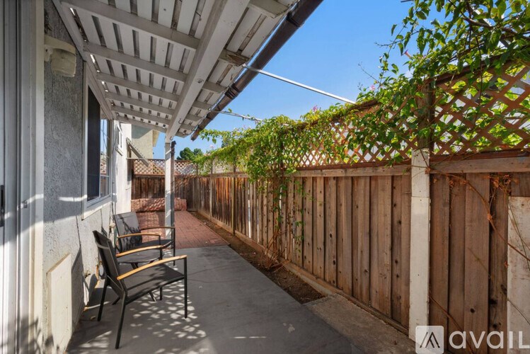 A patio with a bench and a wooden fence.