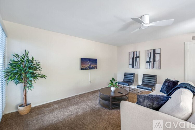 A living room with a couch, chairs, a plant, and pictures on the wall.