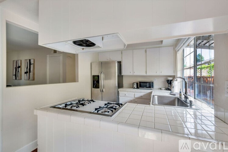A kitchen with white cabinets and a stove top oven.