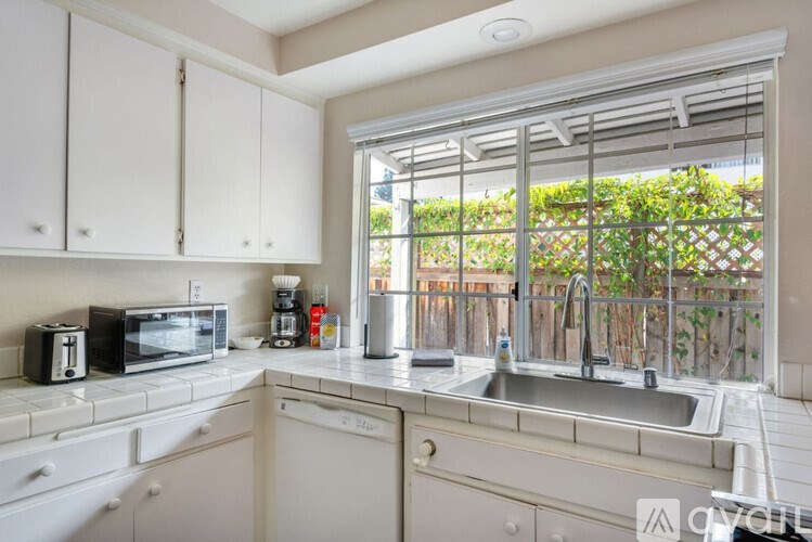 A kitchen with white cabinets and a window overlooking a fence.