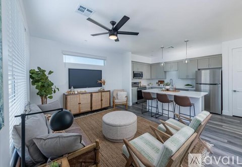 A living room with a grey couch and a black fan.