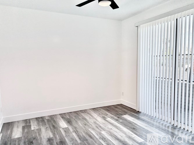 A room with a ceiling fan and a window with blinds.